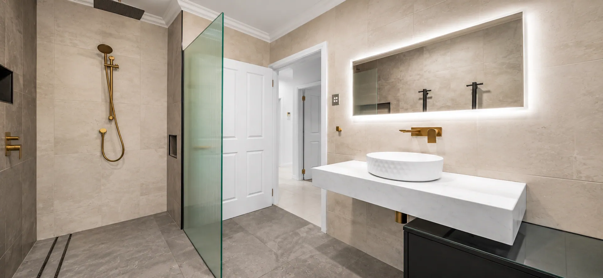 Completed bathroom renovation by Vicinity Plumbing with a walk-in shower and backlit mirror